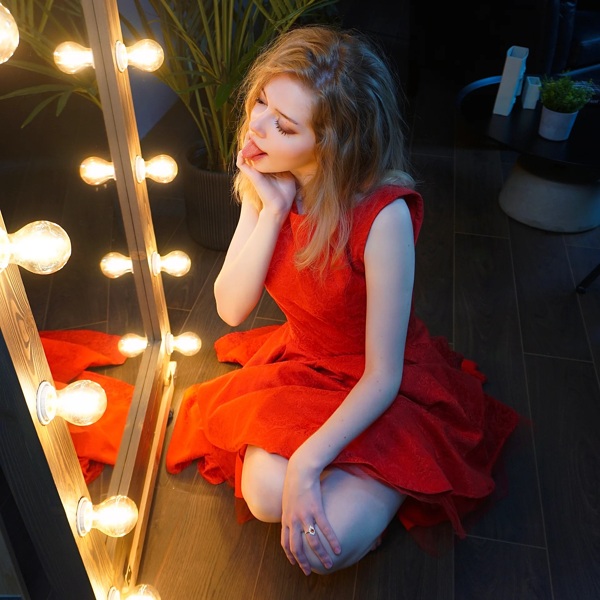 Red dress by a lighted mirror